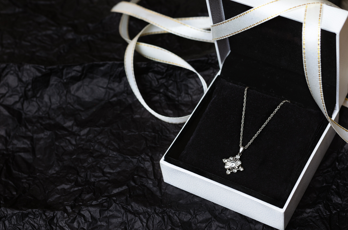 Silver necklace in gift box on black background.